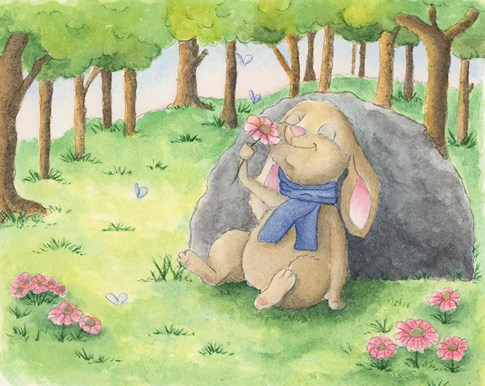 Rabbit with a blue scarf holding a flower by a large rock